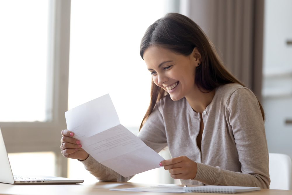 a female member of the college admissions team smiling while reading an impressive letter of recommendation