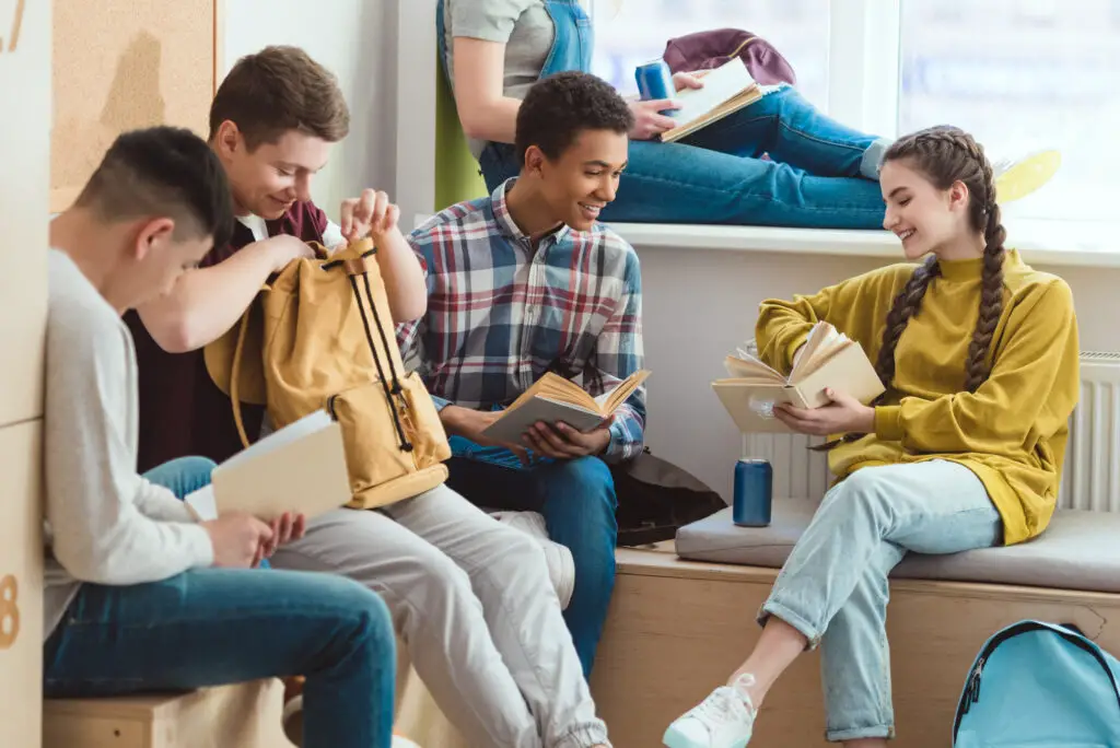 A group of male and female college students seated in a corner reading books