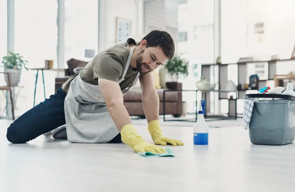 a male college student getting rid of dirt and grime on the floor as an office cleaning side hustle