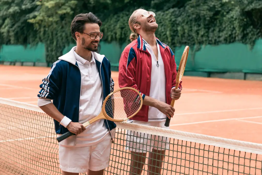 laughing male college students renting tennis rackets on the court