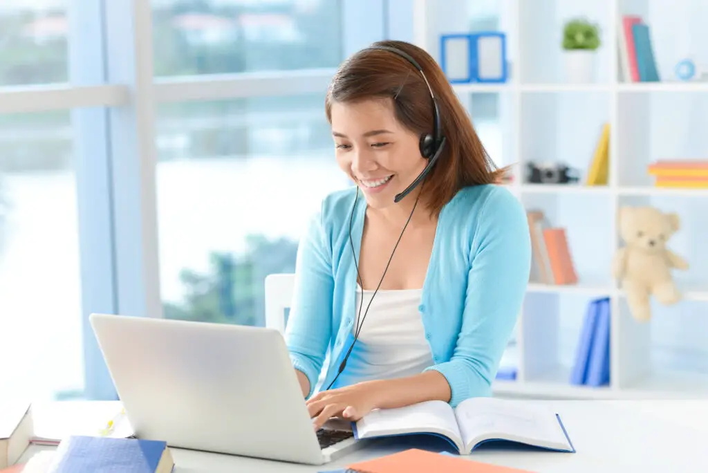smiling female college student doing a side hustle as an audio transcriber using a laptop and headphones