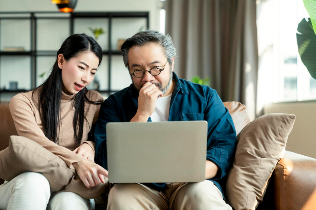 Married Asian couple with a laptop to fill out the parental information needed in the FAFSA