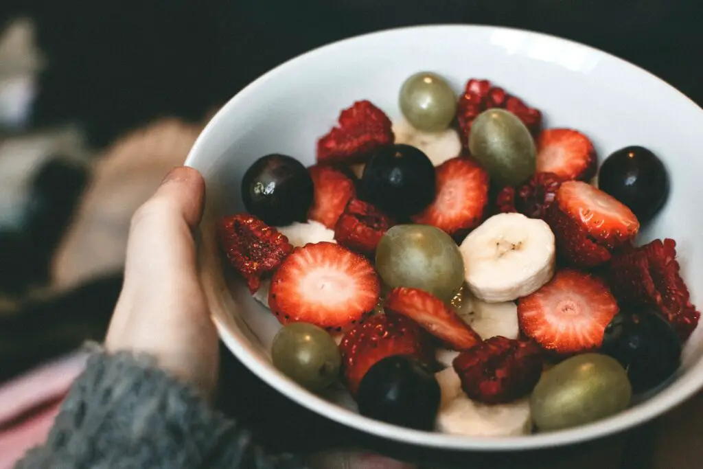 womans-hand-holding-bowl-of-fruit-salad