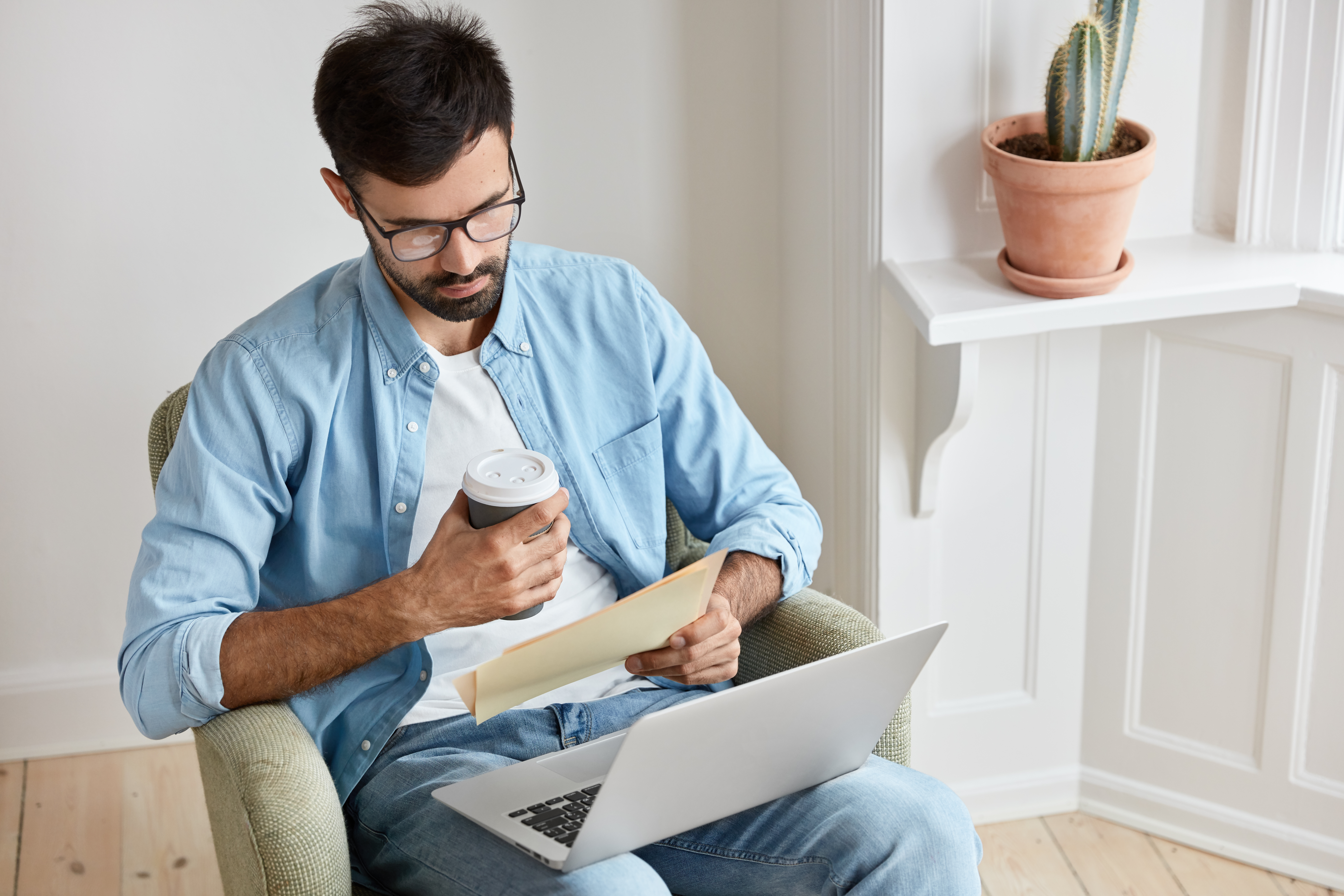 male college student sitting on a chair intently looking at his tax records in order to fill out the FAFSA