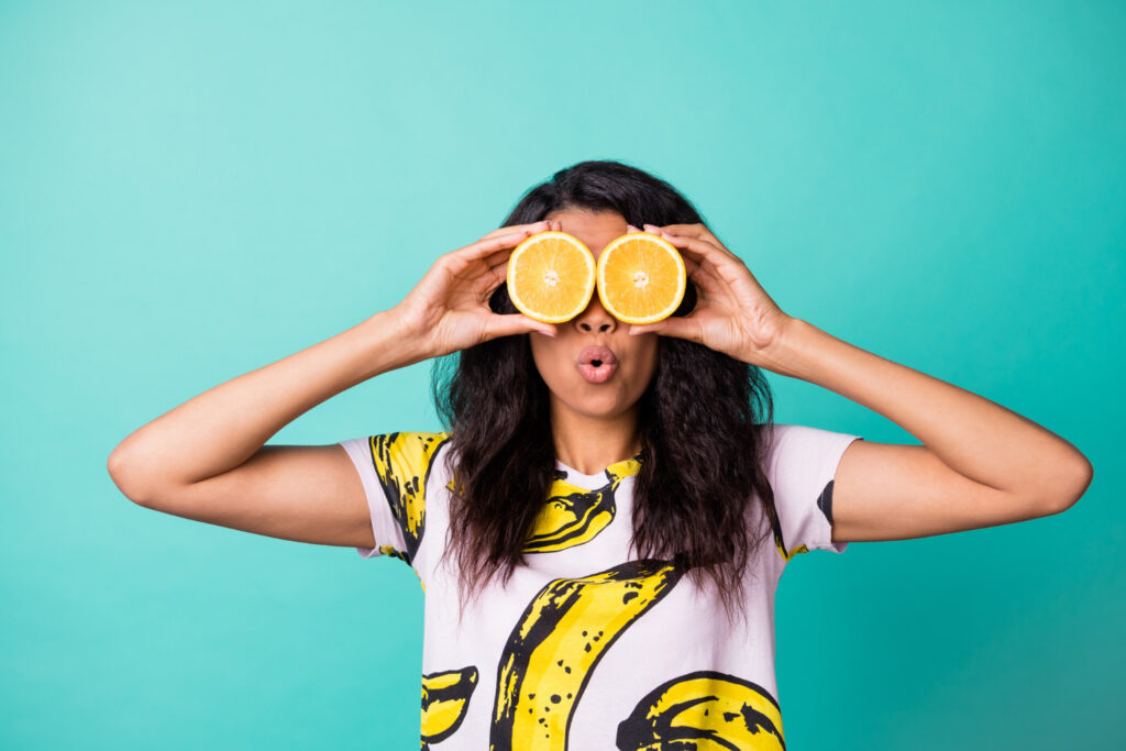 girl-holding-orange-halves-up-as-eyes