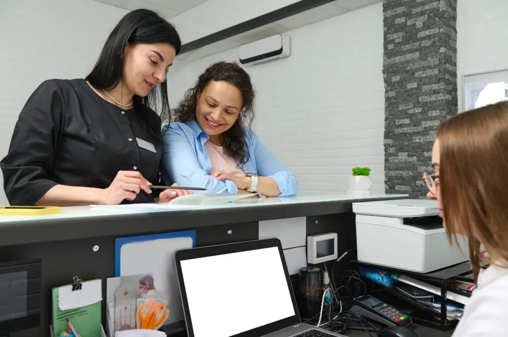 two female college students asking how to transfer college credits at the college admissions office of their new school