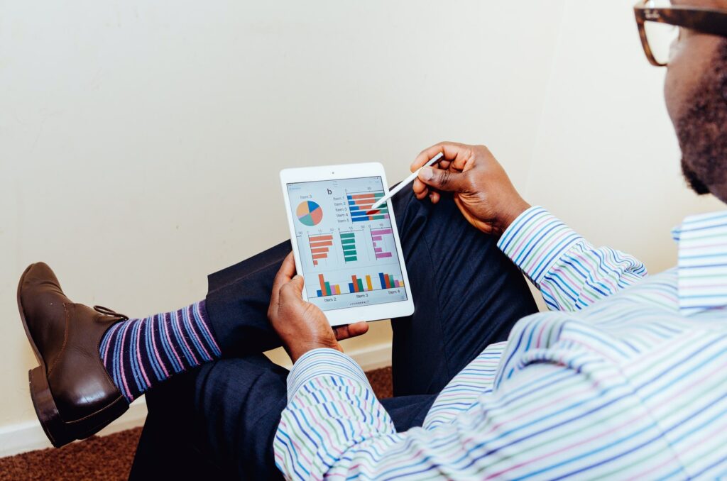 a man in a suit sitting down and looking at charts through his tablet