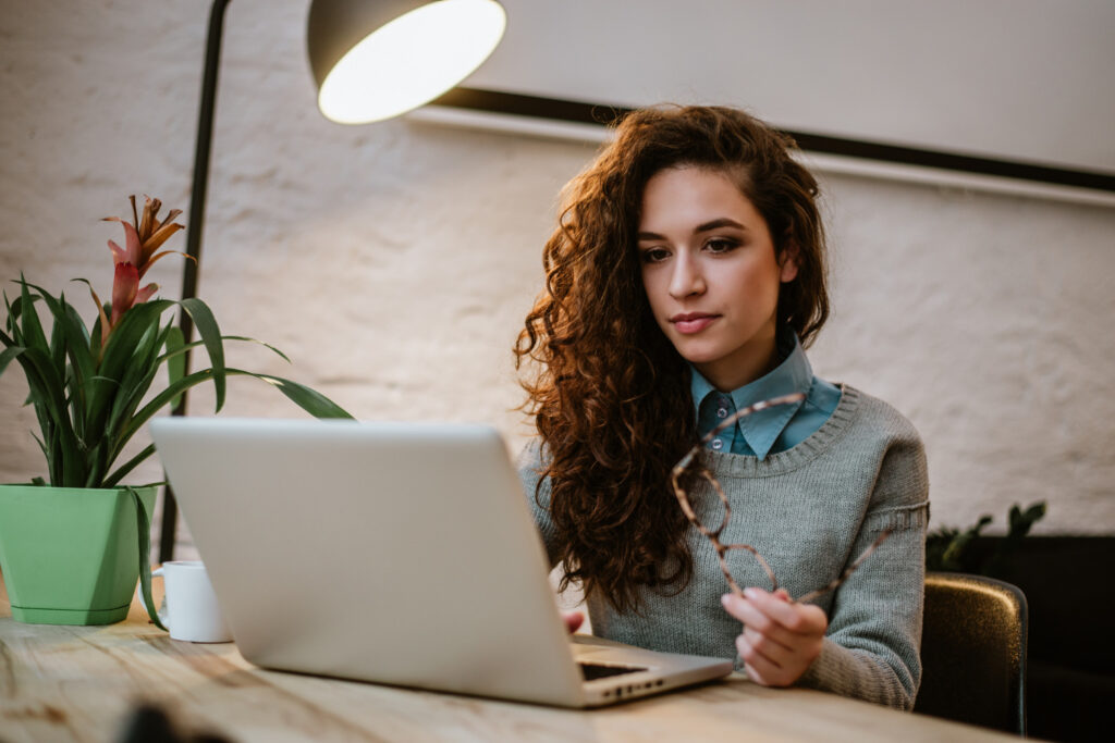 photo-of-young-female-student-writing-at-laptop-for-college