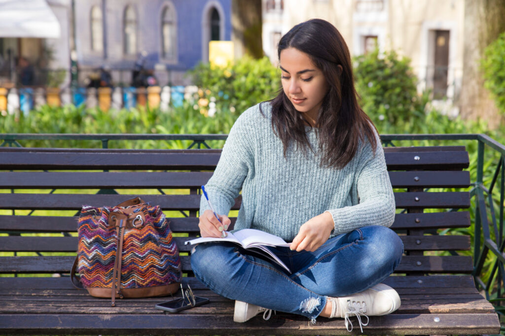 photo-of-college-student-writing-in-notebook-in-park