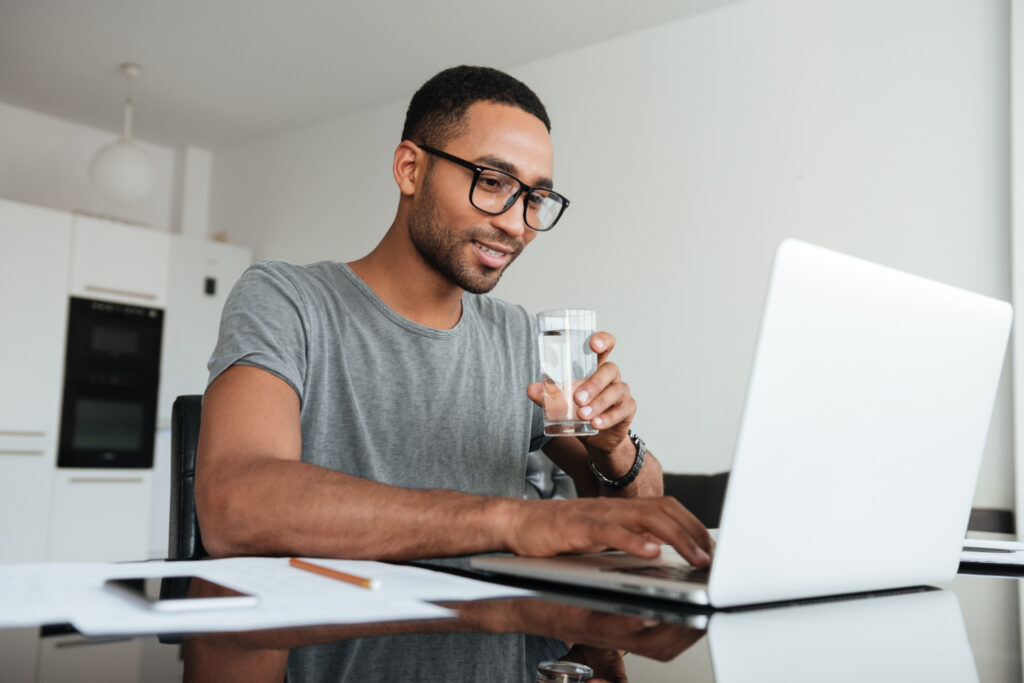 male-student-at-laptop-drinking-water