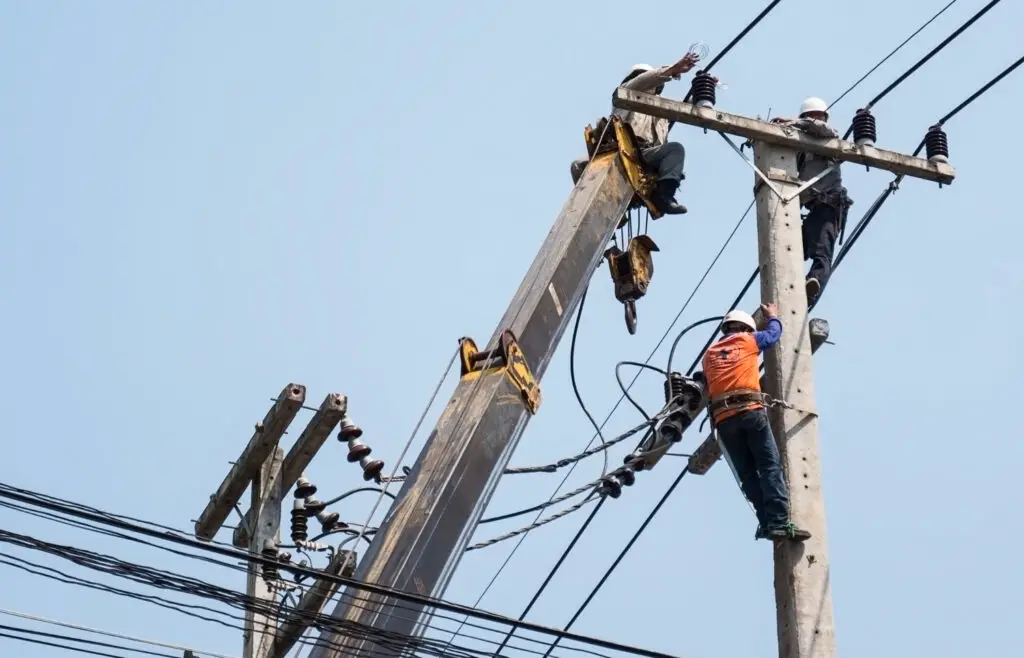 Electricians fixing power transmission lines on a electricity pole