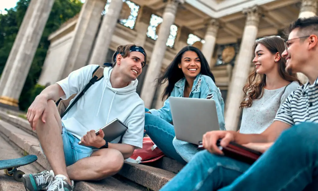 photo-of-writing-students-sitting-on-steps-outside-with-laptop