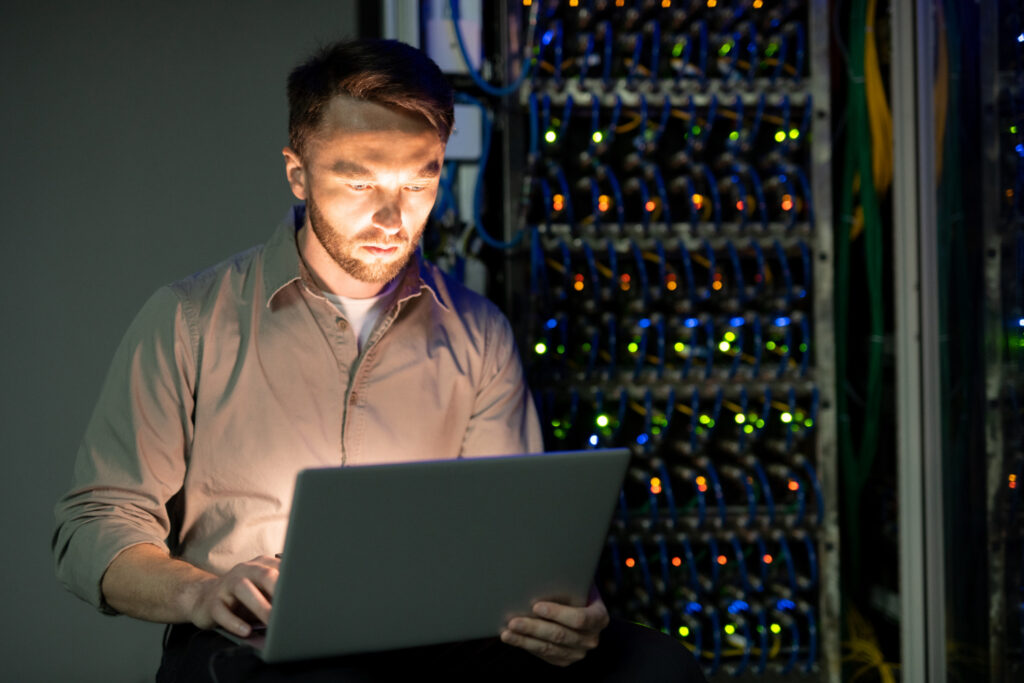 photo-of-male-computer-technician-standing-by-data-rack