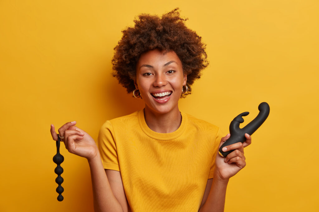 Cheerful woman holding sexual toys