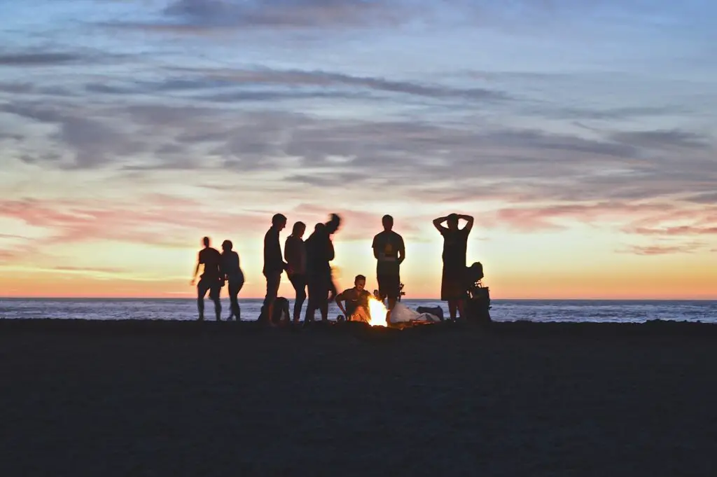 a group of social college students starting a bonfire on a beach