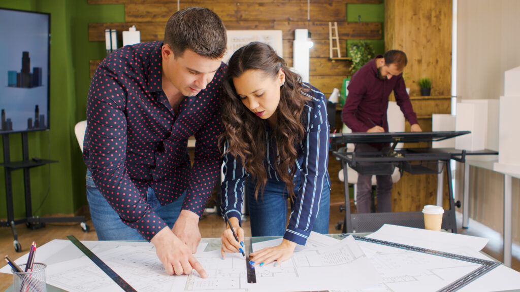 Creative architects working on blueprints in modern office 