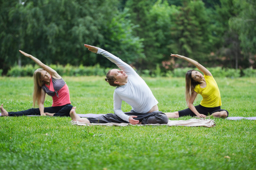 A group of yoga sportsmen performs breathing exercises outdoor