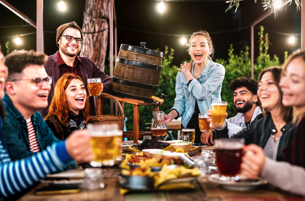 Happy men and women having fun drinking out at beer garden