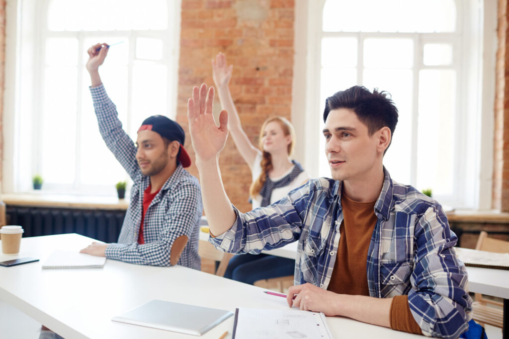 high school students raising their hands while attending AP classes