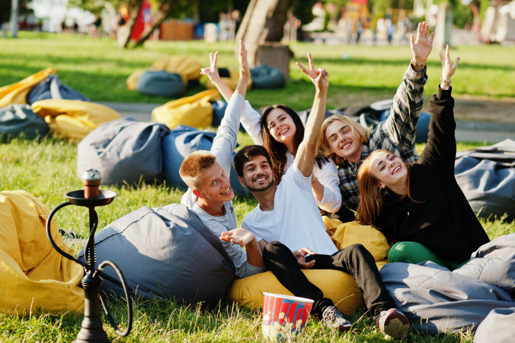 Young multi ethnic group of people watching movie at poof in open air cinema