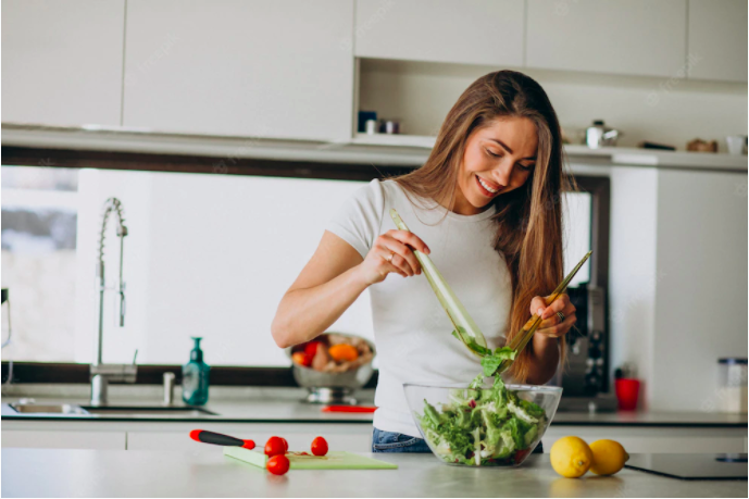 A female student preparing salad in preparation for meatless mondays which lessens carbon emissions