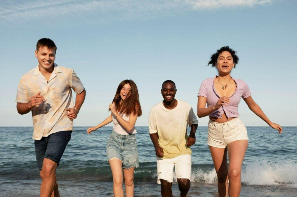 Young men and women run on the beach.