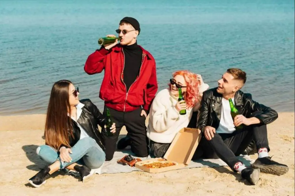 Group of friends drink beer at the beach