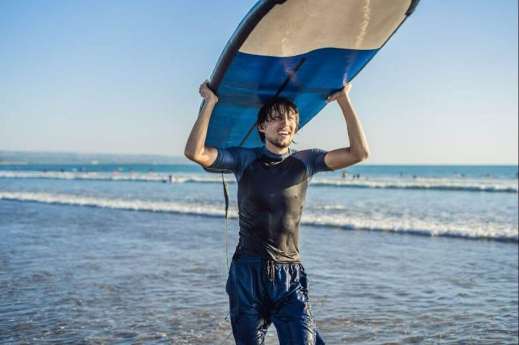 Man carrying surfboard over his head