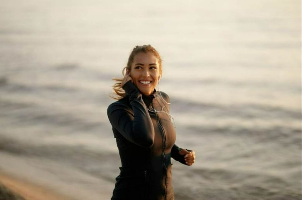 Woman running on the beach while listening to music