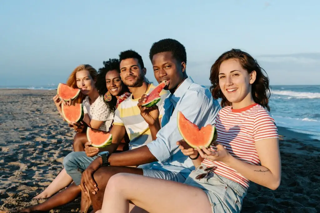 Group of friends having watermelon on the beach.