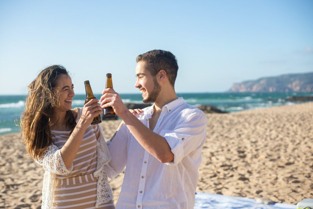 Young group of friends having beer on the beach