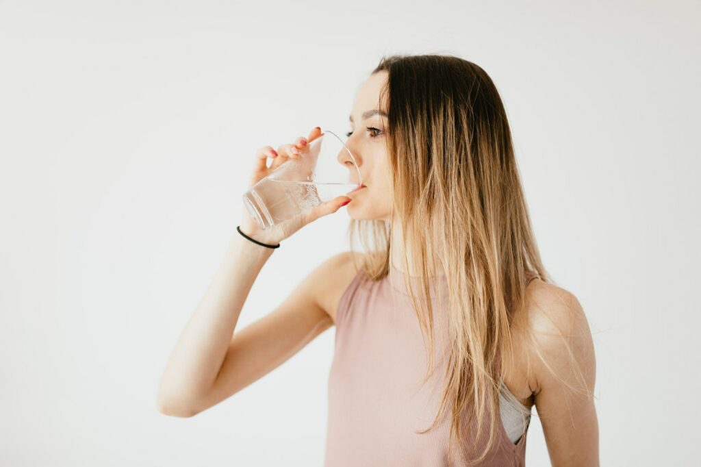 college student drinking a glass of water to prepare for a class presentation