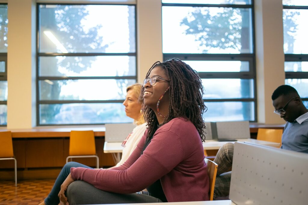 attentive college student smiles at speaker in front of class