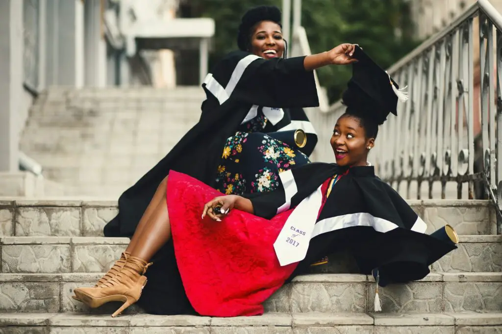 two happy college graduates from an HBCU taking photos on campus steps