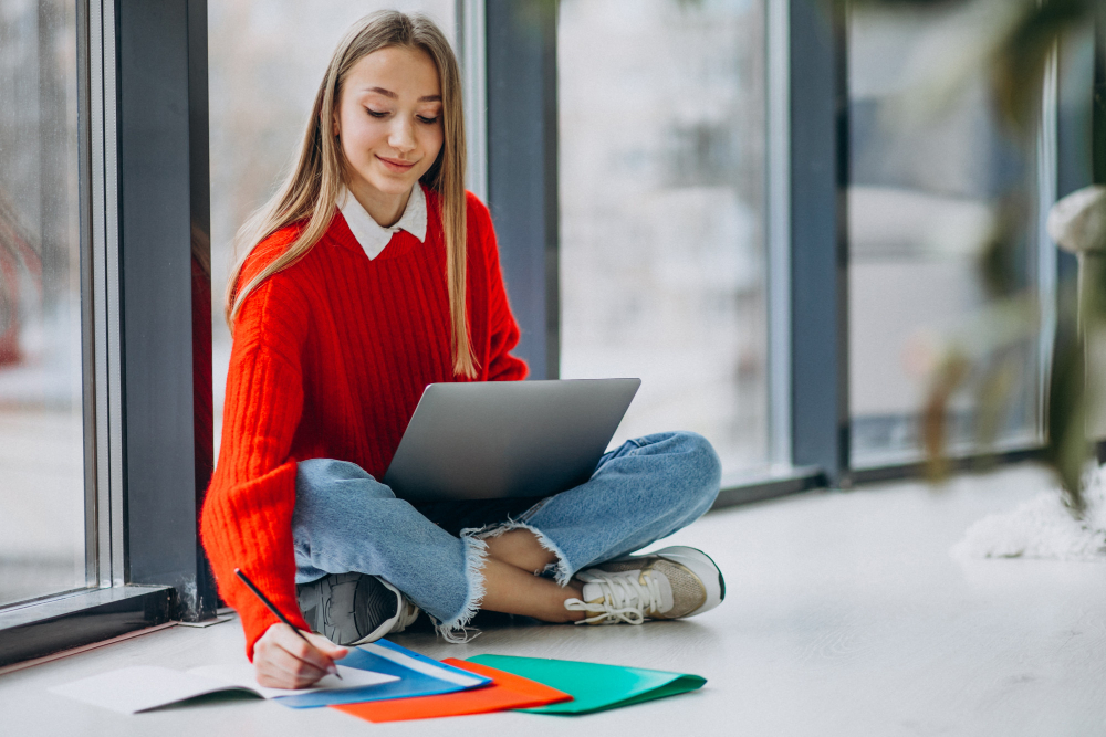 Female student studying on the computer by the window