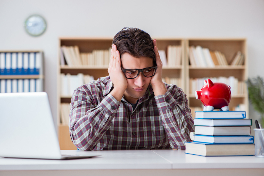 photo-of-student-with-expensive-college-worriedly-looking-at-piggy-bank