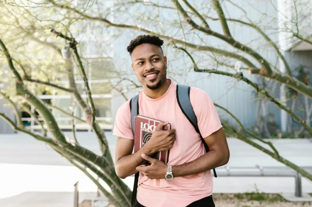 happy-young-african-american-student-holding-books-on-campus-after-being-accepted-to-ivy-league-college
