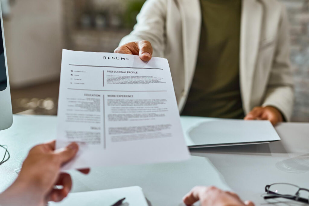 fresh college graduate hands over resume during job interview