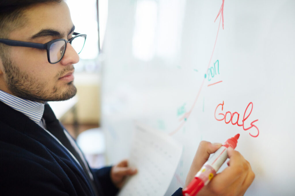 male employee writing down future goals of the team on a whiteboard