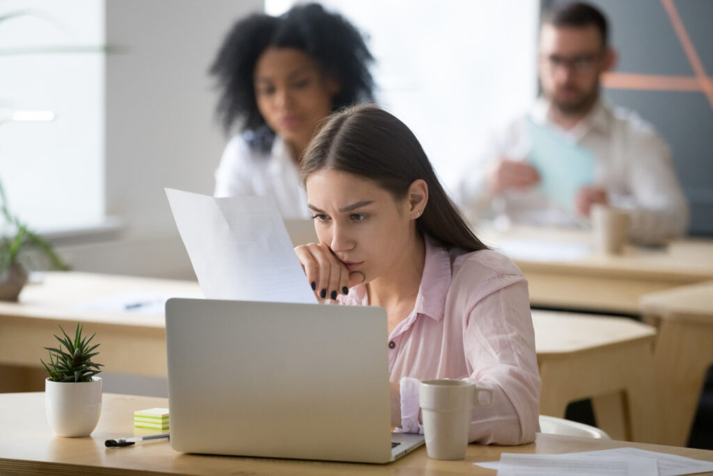 stressed female employee looking at her report after being reprimanded for a mistake