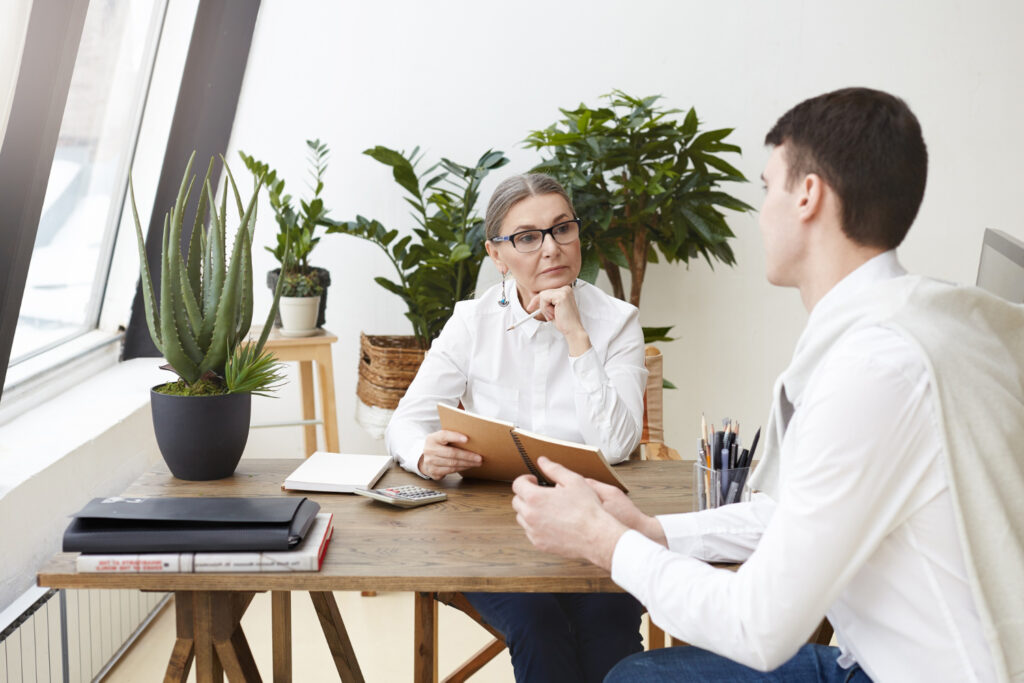 young aspiring candidate asks questions about the job and the company to the interviewer