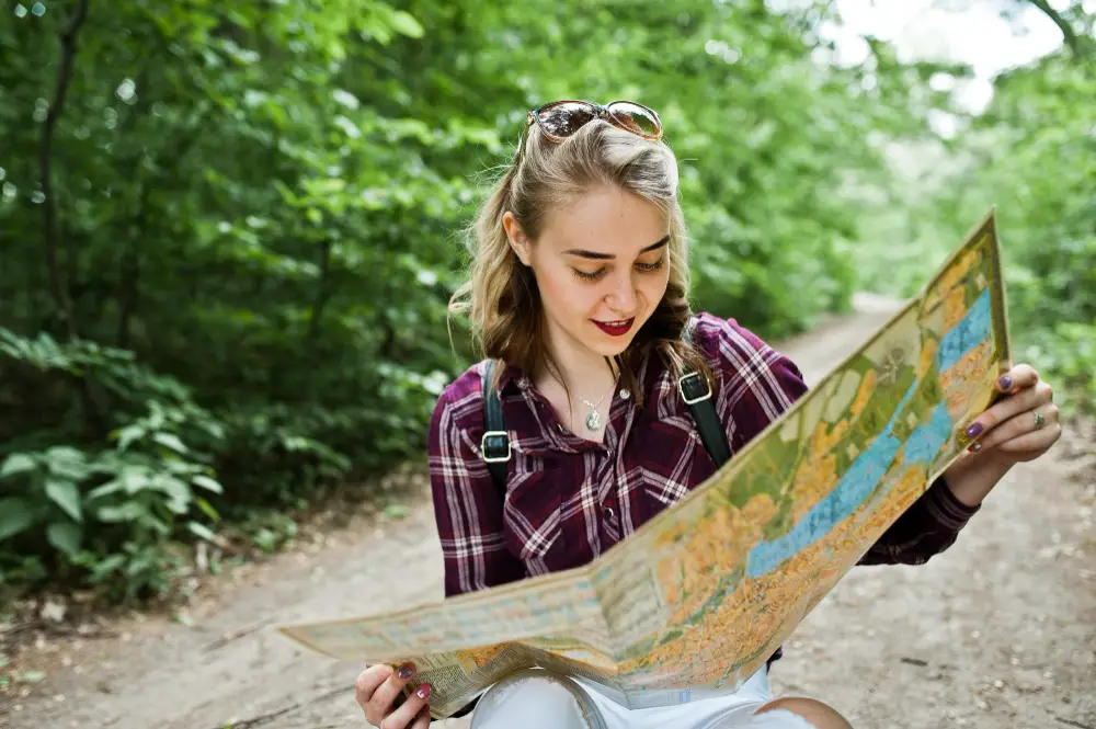 young-female-tour-guide-reading-map-outdoors-during-summer-job
