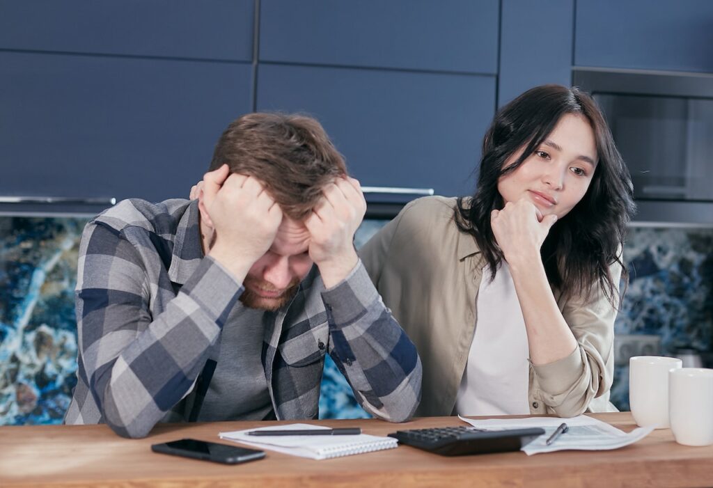 undocumented student unable to pay for college sits with heads in hands with friend looking at bills