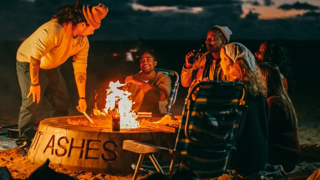 male-and-female-students-getting-warm-by-the-bonfire-at-a-camping-college-party