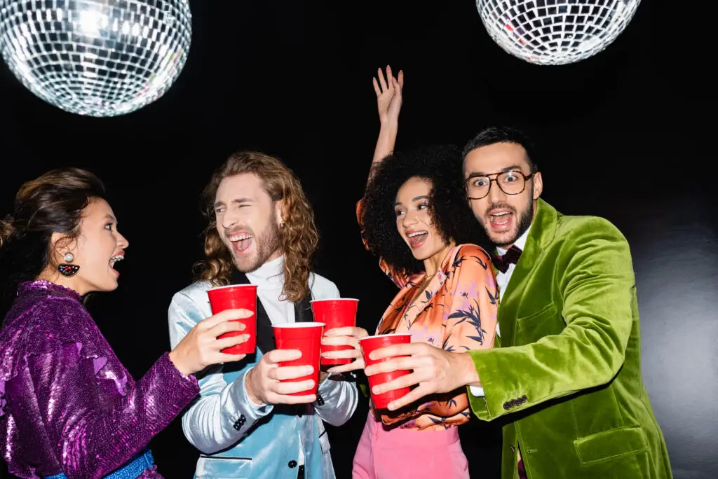 male-and-female-college-students-holding-red-cups-and-dancing-at-a-disco-themed-college-party