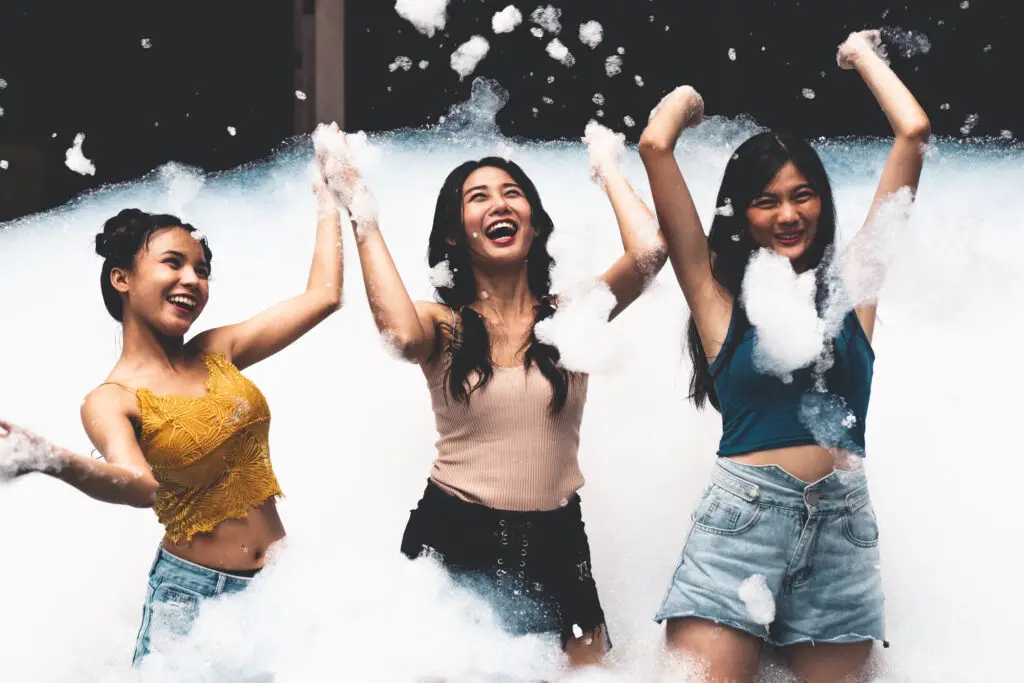 female-students-dancing-and-playing-with-foam-and-bubbles-at-a-college-party