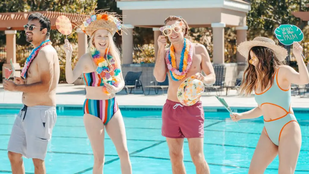 four-students-wearing-leis-and-bathing-suits-by-the-swimming-pool-at-a-tropical-college-party-theme