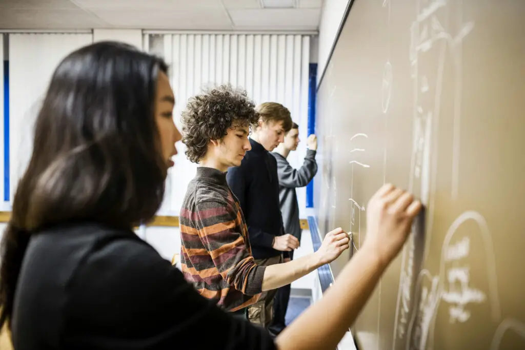 Four college students drawing on a blackboard