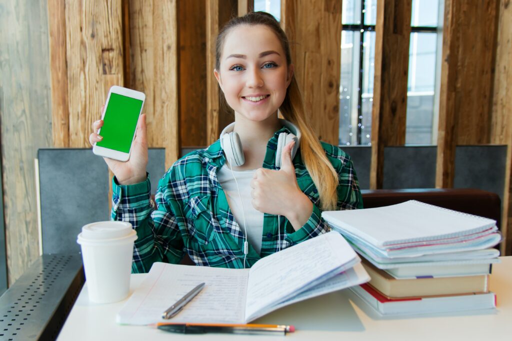 A female college student giving a thumbs up as she completes her portfolio of work for submission to her adviser under a non-traditional grading system