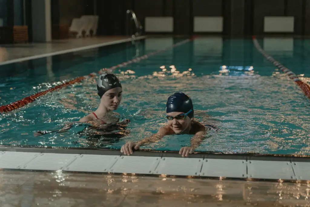 A female college student working as a part-time swimming instructor teaching her student in the pool